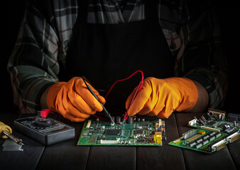 Master tester checks the electronic board in the workshop. Computer or electronics repair service.