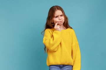 Portrait of little unhealthy girl touching cheek, feeling severe toothache, oral health problems,...
