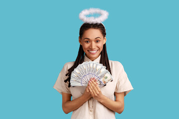 Portrait of satisfied smiling angelic woman with dreadlocks and nimb over head holding fan of...