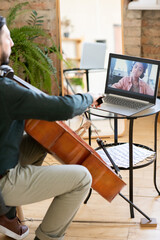 Cute African schoolboy on laptop screen looking at music teacher playing cello while sitting in home environment © pressmaster