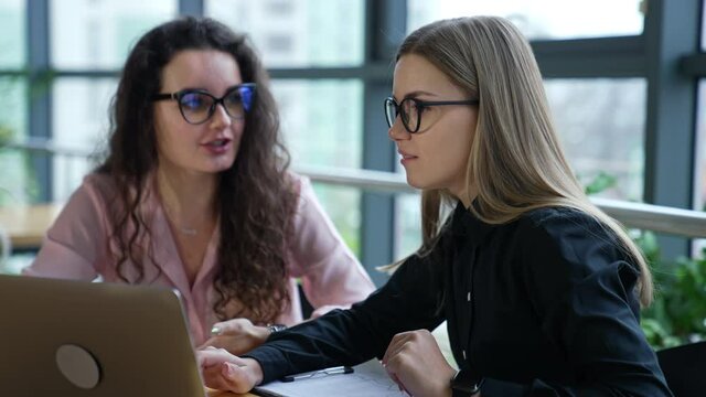 Two ladies in office sit in front of laptop and discuss strategies. Business conversation of two female colleagues. Business ladies close up.