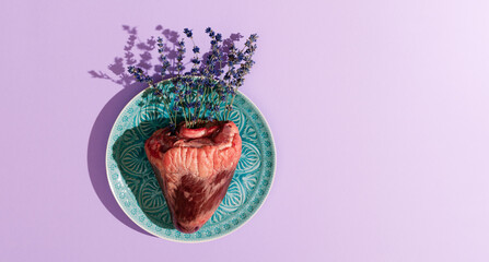 Naklejka premium Top view of animal heart filled with lavender flowers on turquoise plate. Creative love, St Valentine holiday, concept.