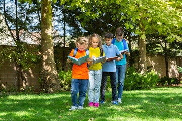 Group of happy school child with book in outdoor park