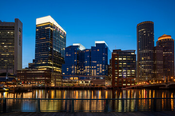 Fototapeta na wymiar Panoramic picturesque city view of Boston Harbour and Seaport Blvd evening and night time, Massachusetts. An intellectual, technological and political center. Building exteriors of financial downtown.