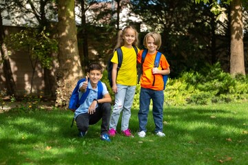 Fototapeta premium Group of happy school child with schoolbag in outdoor park