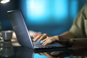 Woman hands typing on laptop in the night at home