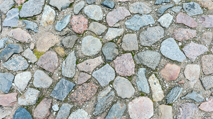a fragment of a cobblestone pavement of different sizes and shapes. Close-up. Weathered surface