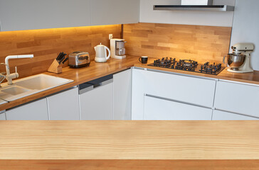 Empty wooden table top or countertop corner with blurred modern kitchen background.	