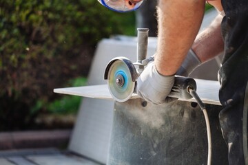 Locksmith in special clothes and goggles works in production. Ceramic processing with angle...