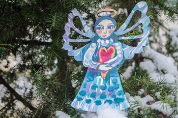 Acrylic painted wooden angel on the background of the Christmas tree