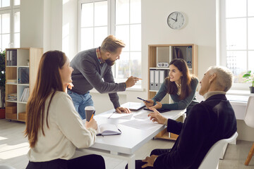 Team of young and senior people having a work meeting around an office table, discussing new ideas,...