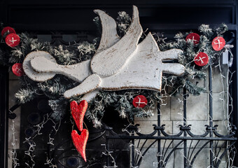 Wooden angel with a red heart on an ancient dark door.