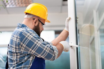 Young repairman fixing window frame in room at daytime