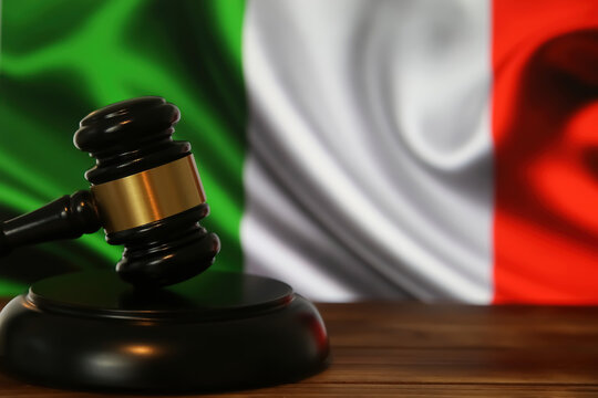 Closeup of isolated judge wood gavel with blurred italy flag background (focus on hammer head)