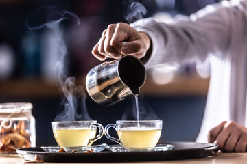 The bartender pours hot mulled wine or a winter whiskey drink Hot Teddy