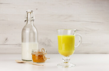 A glass of golden milk, turmeric beverage and ingredients
