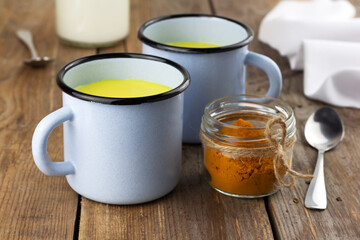 Two cups of golden milk, ayurvedic turmeric beverage and ingredients