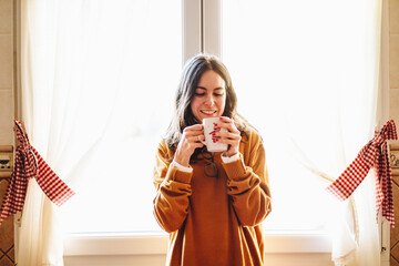 young woman drinking cup of coffee in kitchen