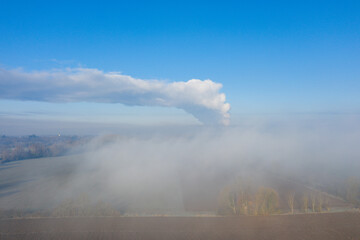 Fototapeta na wymiar Steam from a nuclear power station above the countryside in Europe, France, the Center region, Loiret, towards Orleans, in Winter, on a sunny day.