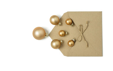 Open envelope from craft paper from which Christmas golden balls have spilled out.