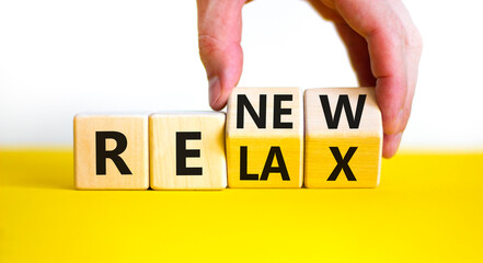 Relax and renew symbol. Businessman turns cubes and changes the word 'relax' to 'renew'. Beautiful yellow table, white background. Business, relax and renew concept. Copy space.