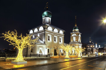Fototapeta na wymiar Varvarka Street with the ancient temple of Maxim the Confessor, the bell tower and the Temple of Varvara the Great Martyr at night on Christmas holidays. Moscow, Russia