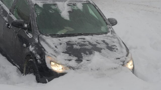 Blizzard snow wind and cold weather in winter storm, car covered with snow stuck in a snowdrift. High quality 4k footage