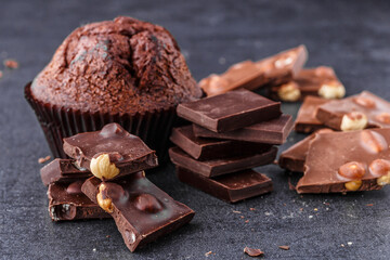Chocolate cupcake with icing and chocolate bar in Dark lighting,Homemade delicious chocolate muffin on wooden background close-up