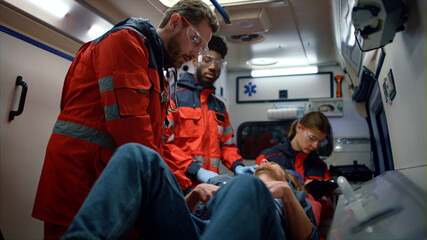 Mixed race medical team giving first aid help in ambulance car