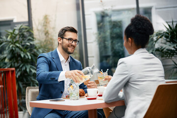 Happy businessman and his female colleague having breakfast in cafe.