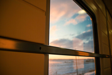 view from the window of a high-speed train in the aisle of a compartment, at sunset, the foreground and background are blurred with bokeh effect