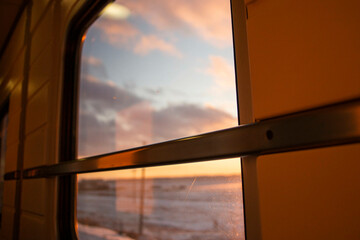 view from the window of a high-speed train in the aisle of a compartment, at sunset, the foreground and background are blurred with bokeh effect