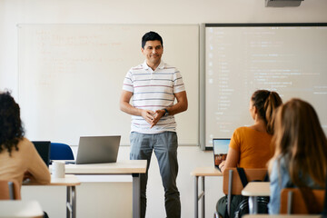 Computer science teacher gives lecture to group of high school students in classroom.