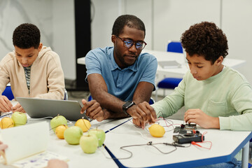 Portrait of African-American teacher working on science experiments with diverse group of children