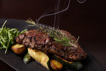 Grilled striploin steak on black dish. steak with fried potatoes and vegetables