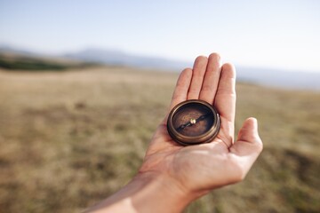 Hiking hand holding classic compass on natural background