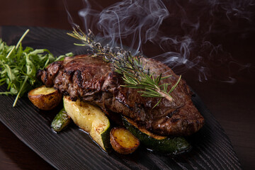 Grilled striploin steak on black dish. steak with fried potatoes and vegetables