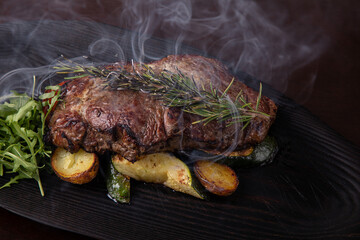 Grilled striploin steak on black dish. steak with fried potatoes and vegetables