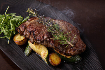 Grilled striploin steak on black dish. steak with fried potatoes and vegetables