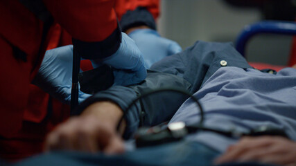 Man lying on stretchers. Medical worker putting tonometer on patient arm 