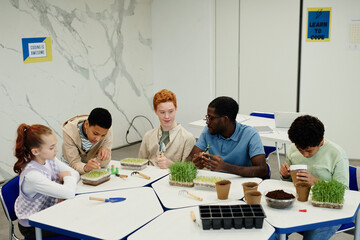 Young African-American teacher working on biology experiments with diverse group of children in...