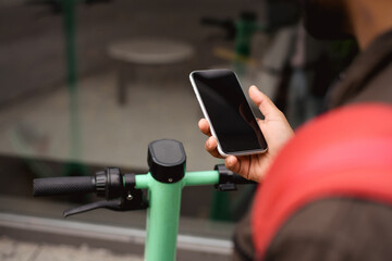 Cropped shot of indian man holding smartphone with blank screen near public eclectic scooter outdoors 