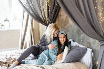 Woman and young girl lying in bed smiling
