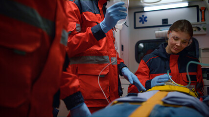 Fototapeta premium Emergency doctors providing first aid help to patient in emergency car