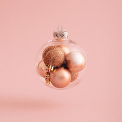 Flying or levitate Christmas ball with xmas baubles inside with sunny day shadow. Creative idea on pink powder background. Minimal New Year transparent concept with place for text or banner. - obrazy, fototapety, plakaty