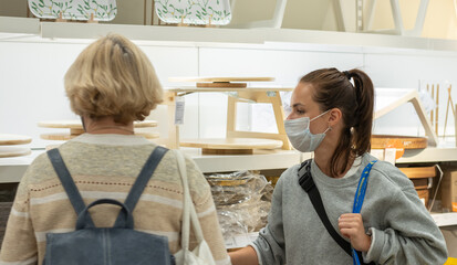 Obraz premium Two women in protective face masks shopping in the store.