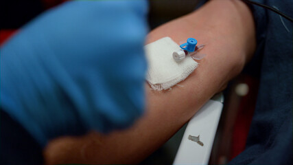 Paramedic inserting needle cannula in arm. Worker placing IV catheter into vein 