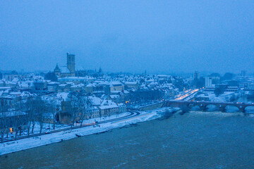 Fototapeta premium The city center of Nevers and its Loire bridge under the snow in Europe, France, Burgundy, Nievre, in Winter, during a cloudy evening.