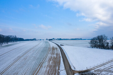 A road crosses the countryside under the snow in Europe, France, Normandy, between Dieppe and Fecamp, in Winter, on a sunny day.