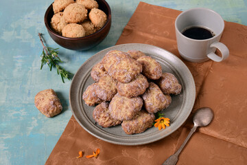 Two types of cookies on plates, coffee in a cup, coffee-colored napkin, turquoise background.
